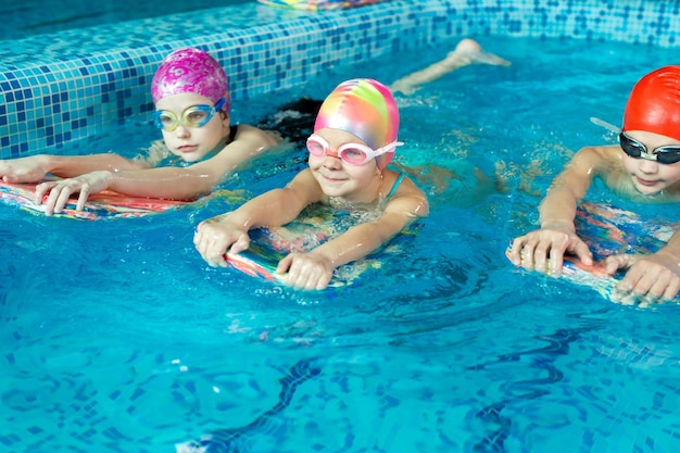 Un groupe de garçons et de filles s'entraîne et apprend à nager dans la piscine avec un instructeur