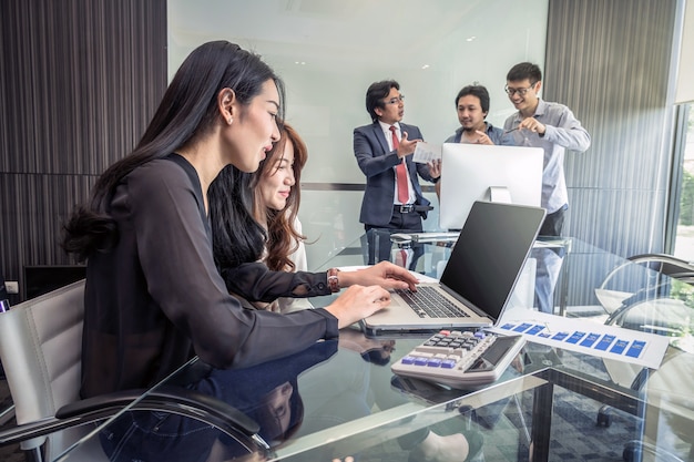 Groupe de gens d&#39;affaires asiatiques avec costume décontracté de travail et de parler ensemble dans le bureau moderne, p