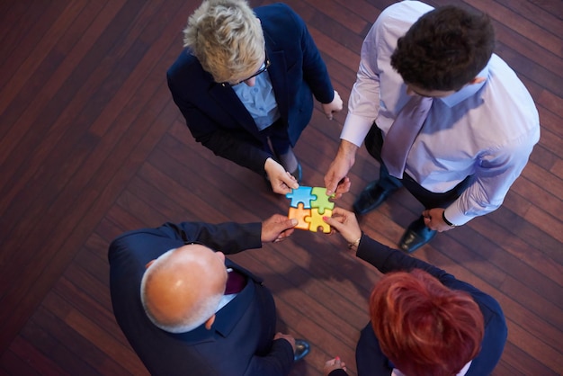 Photo groupe de gens d'affaires assemblant un puzzle et représentant le concept de soutien et d'aide de l'équipe, vue de dessus à l'intérieur de bureau moderne et lumineux