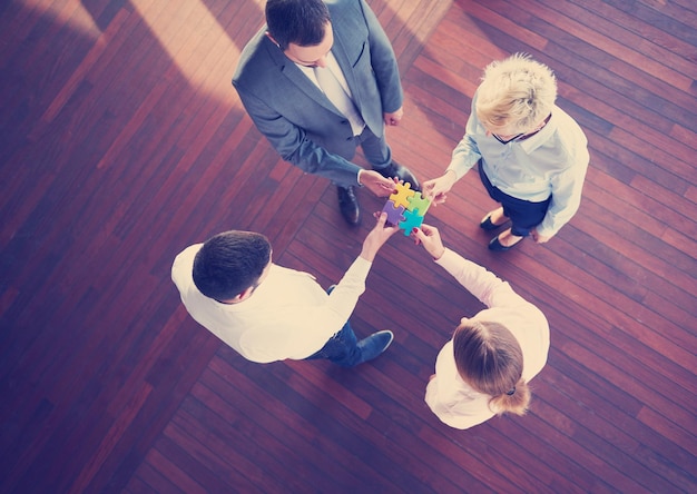 groupe de gens d'affaires assemblant un puzzle et représentant le concept de soutien et d'aide de l'équipe, vue de dessus à l'intérieur de bureau moderne et lumineux