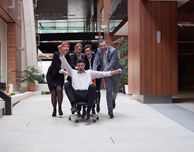 groupe de gens d'affaires au bureau moderne à l'intérieur s'amuser et pousser la chaise de bureau dans le couloir