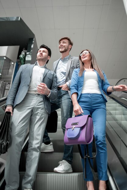 Groupe de gens d'affaires debout sur l'escalator et levant les yeux