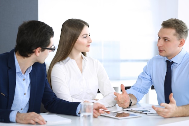 Groupe de gens d'affaires discutant de questions lors d'une réunion dans un bureau moderne. Gestionnaires à la négociation ou au remue-méninges. Travail d'équipe, partenariat et concept d'entreprise