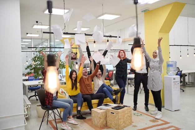 Photo groupe de gens d'affaires jetant du papier dans l'air au bureau de démarrage moderne, succès d'équipe et concept de travail accompli