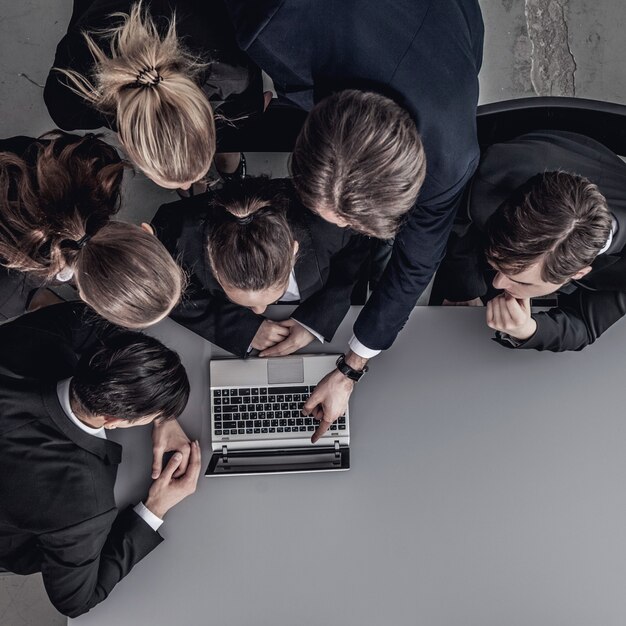 Un groupe de gens d'affaires regarde ensemble un ordinateur portable au bureau