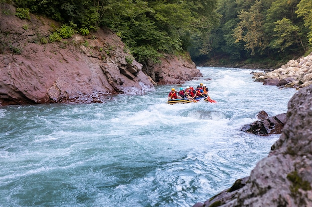 Groupe de gens heureux avec guide de rafting en eau vive et d'aviron sur la rivière.