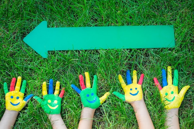 Groupe de gens heureux sur l'herbe verte Enfants s'amusant au printemps Smiley sur les mains Concept de travail d'équipe Portrait vue de dessus