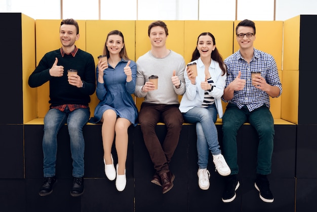 Groupe de gens joyeux parlent autour d'une tasse de café dans un espace créatif.