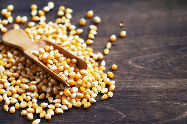 Groupe de grains de maïs crus jaunes maïs sucré. Graines de céréales ingrédient grain de maïs doré. Fond de pop-corn mûr de table en bois.