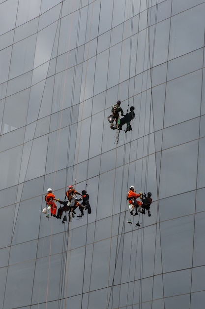 Groupe de grimpeurs industriels nettoyage service de fenêtres sur immeuble de grande hauteur.