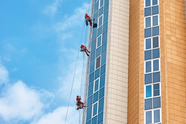 Groupe de grimpeurs industriels travaillent sur un bâtiment moderne en plein air