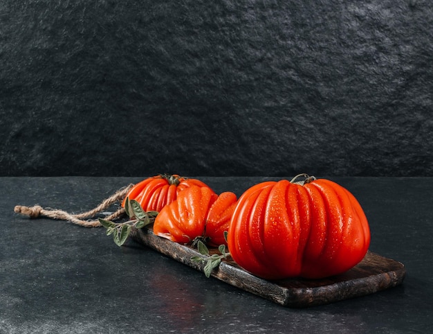 Un groupe de grosses tomates Costoluto avec de l'origan sur un espace de fond gris pour le texte