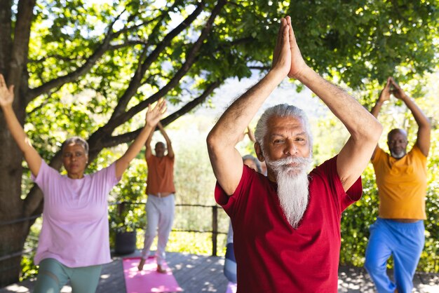 Photo un groupe heureux et diversifié d'amis âgés pratiquant le yoga dans un jardin ensoleillé.