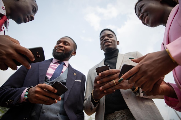 Groupe d'hommes d'affaires africains ayant une conversation des gens élégants se parlent et utilisent leur smartphone photo d'en bas