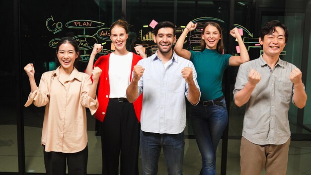 Photo un groupe d'hommes d'affaires applaudissent pour célébrer le succès du projet en regardant la caméra une équipe d'affaires professionnelle et diversifiée se tient devant un mur de verre avec la stratégie de marketing ideaplan tracery