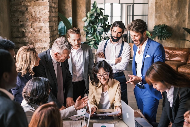 Groupe d'hommes d'affaires autour de leur patron discutant de la meilleure stratégie commerciale