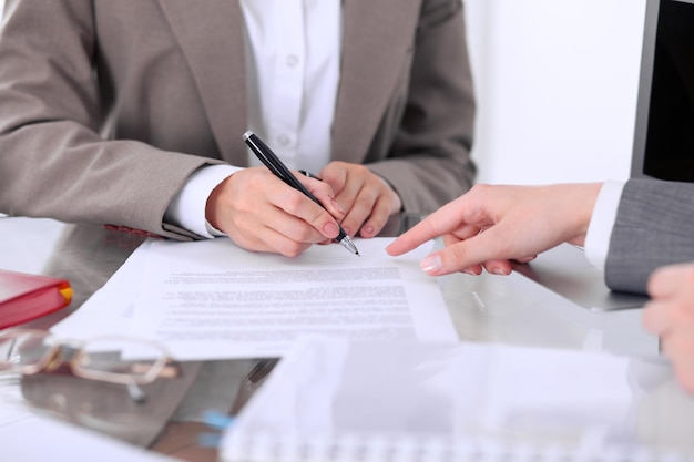 Groupe d'hommes d'affaires et d'avocats discutant d'un contrat assis à la table La femme chef signe des papiers