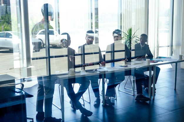 Un groupe d'hommes d'affaires et de femmes d'affaires afro-américains européens arabes et coréens prospères travaillant au bureau avec de grandes baies vitrées