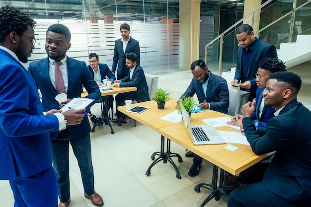 Groupe d'hommes d'affaires internationaux regardant le graphique sur un tableau à feuilles mobiles dans un bureau écologique moderne