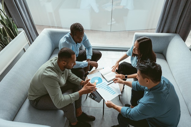 Groupe d'hommes d'affaires multiethniques travaillant ensemble sur un projet assis dans un bureau moderne