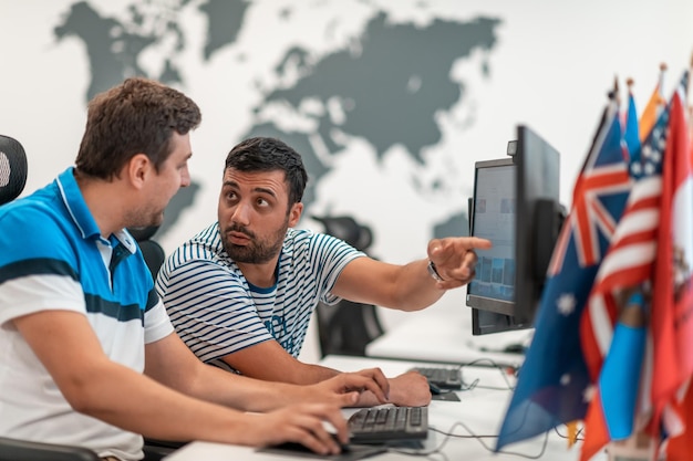 Groupe d'hommes d'affaires occasionnels travaillant sur un ordinateur de bureau dans un intérieur de bureau de démarrage à aire ouverte moderne. Mise au point sélective. Photo de haute qualité