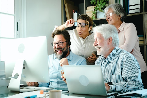 Groupe d'hommes et de femmes d'affaires au bureau au travail regarde l'ordinateur l'heureuse conclusion d'un projet