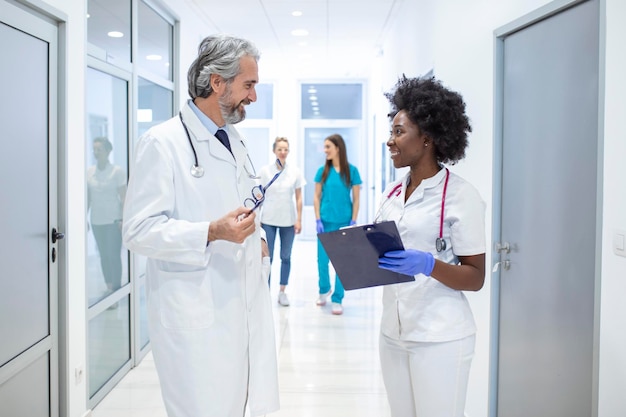 Groupe d'infirmiers avec presse-papiers discutant le long du couloir de l'hôpital Médecin et infirmière informant le rapport médical