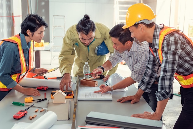 Un groupe d'ingénieurs travaillant sur un plan sur une table au bureau.