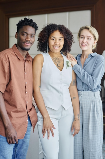 Groupe d'invités de mariage interculturels heureux et mariée élégante en costume blanc