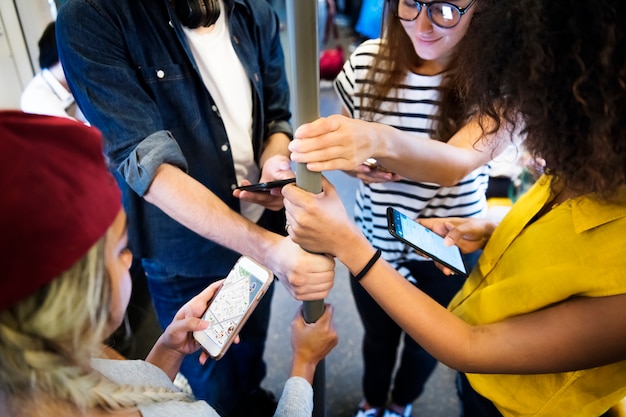 Photo groupe de jeunes amis adultes utilisant des smartphones dans le métro