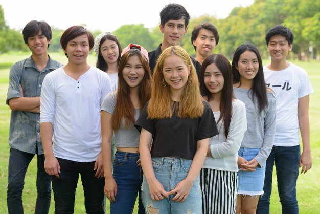 Groupe de jeunes amis asiatiques traîner et se détendre ensemble dans le parc en plein air