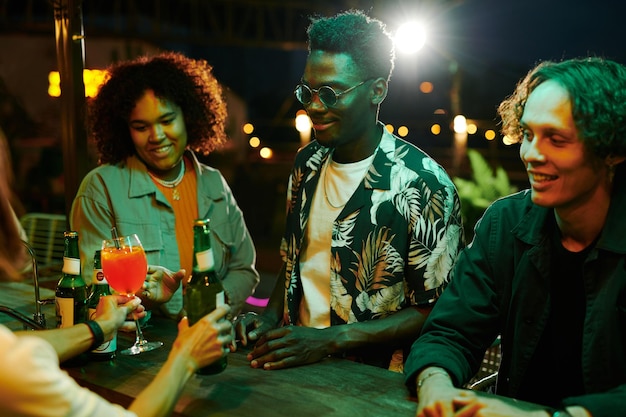 Groupe de jeunes amis interculturels prenant des cocktails et de la bière commandés