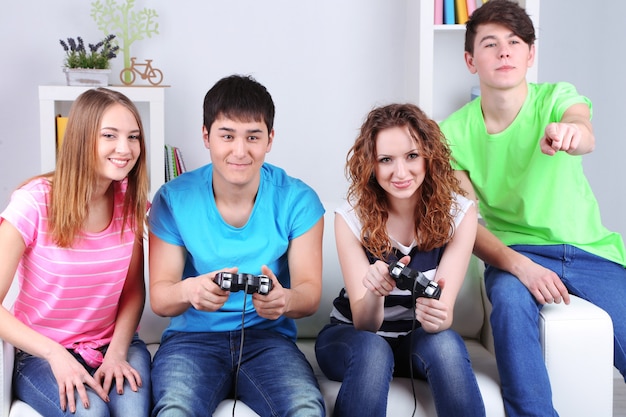 Groupe de jeunes amis jouant à des jeux vidéo à la maison