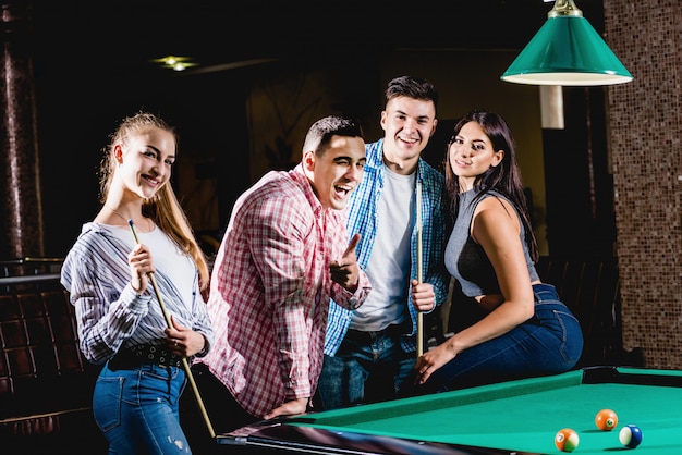 Groupe de jeunes amis joyeux jouant au billard.