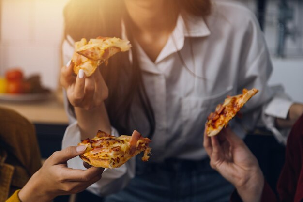 Groupe de jeunes amis mangeant de la pizza à la maison et s'amusant