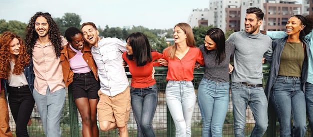 Groupe de jeunes amis multiethniques des années 20 s'embrassant joyeusement dans le parc en parlant et en plaisantant ensemble des personnes multiculturelles debout les mains sur les épaules ensemble concept de mode de vie des gens