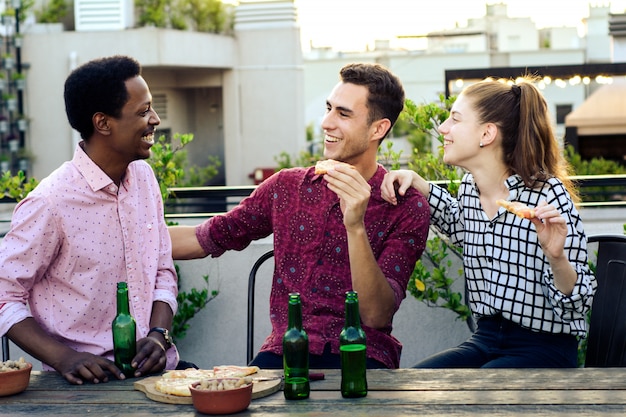 Groupe de jeunes amis avec pizza et bouteilles de boisson