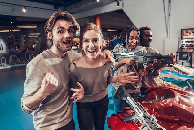 Groupe de jeunes amis posant avec des fusils noirs en arcade.