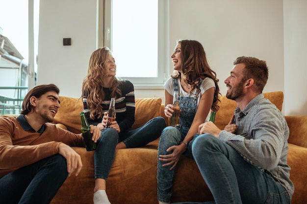 Groupe de jeunes amis se détendre et prendre un verre ensemble à l'intérieur