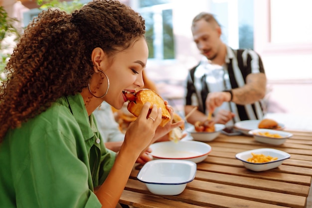 Groupe de jeunes amis se réunissant dans un café mangeant des hamburgers frais et savoureux Restauration rapide