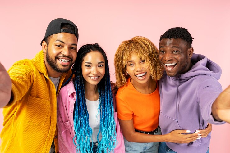 Photo groupe de jeunes amis souriants prenant des selfies embrassant debout ensemble isolés sur fond rose