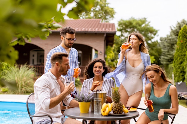 Groupe de jeunes applaudissant avec du cidre au bord de la piscine dans le jardin