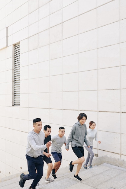 Groupe de jeunes asiatiques en forme en vêtements de sport montant les escaliers