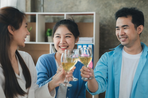 Groupe de jeunes Asiatiques tintant des verres à vin blancs fêtes d'entreprise de démarrage fêtes du Nouvel An fêtes d'entreprise annuelles boissons alcoolisées fête des employés de l'entreprise idées de restauration célébrations