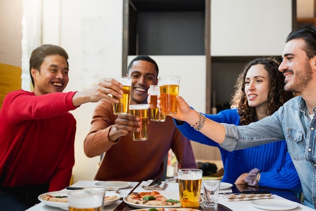 Groupe de jeunes assis à table dans un restaurant Les amis célèbrent avec un verre de bière