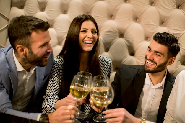 Groupe de jeunes célébrant et grillant avec du vin blanc