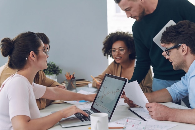 Un groupe de jeunes confiants discute d'affaires lors d'une réunion au bureau.