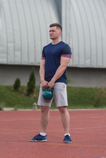 Un groupe de jeunes en cours d'aérobic faisant un exercice Kettle Bell en plein air