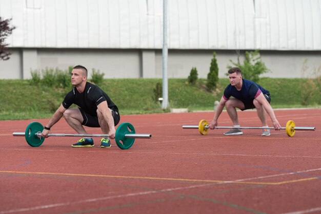 Un groupe de jeunes en cours d'aérobic faisant un exercice de squat aérien en plein air