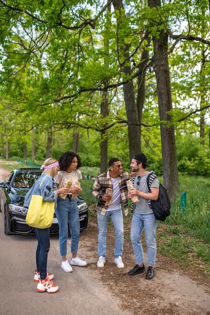 Groupe de jeunes debout dans la forêt près de la voiture